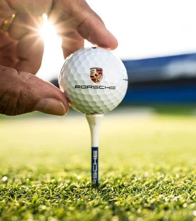 Golfball mit Porsche-Wappen auf dem Tee