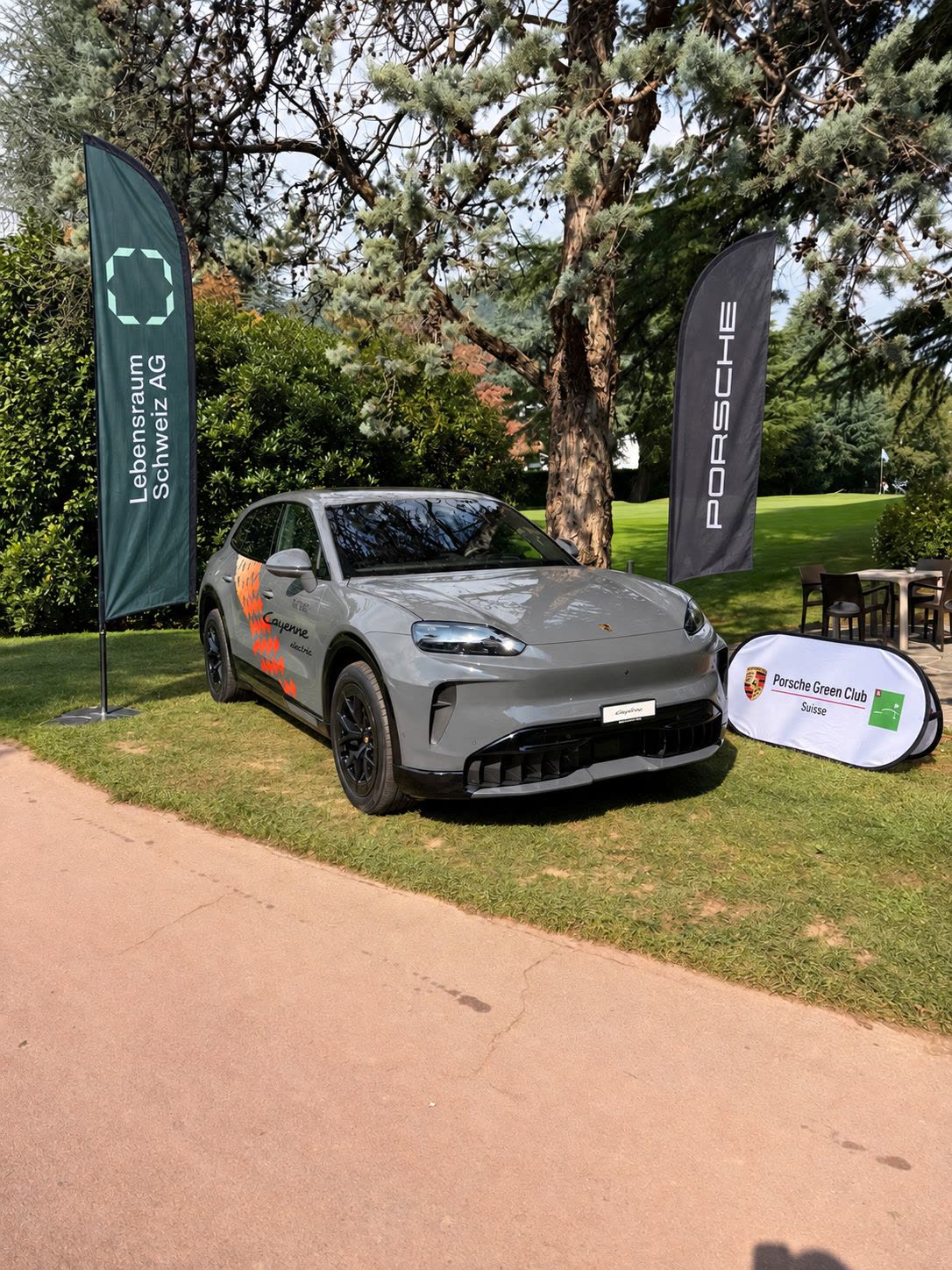 Fahne der Lebensraum Schweiz AG neben dem Porsche Cayenne Electric am Golf Club Lugano